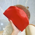 Elegant red satin evening clutch with gold rhinestone frame held in hand as variant - Red