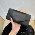 Dettaglio macro dell'elegante trama in raso plissettato e piegatura sulla borsa da sera - Nero