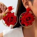 Close-up of oversized red velvet rose earrings with gold metal hoops on a model - Red Ring Style