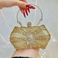 Luxuriöse goldene Glitzer-Clutch mit Schleifenrahmen und Strass-Stern in der Hand - Gold