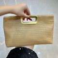 Natural straw clutch bag with golden metallic handle held by hand for summer outfit - Beige-Striped