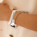 Gros plan d'un large bracelet manchette géométrique ouvert en argent poli au poignet - Style Rectangulaire Élargi Argenté (28749-silvery)