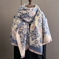 Nahaufnahme des floralen Jacquard-Musters und weicher Fransen am Winter-Schultertuch - Blau