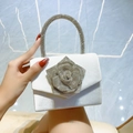 White satin evening bag with oversized silver rhinestone rose flower held by hand - White