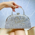 Silver evening clutch bag with sparkling rhinestones and metal handle held by hand - Silver