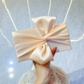 Elegant champagne gold satin evening clutch with a large bow held by a model - Apricot