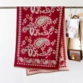 Close-up of red paisley jacquard shawl with tassel details and knit texture - Paisley Red