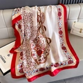 Close-up of vintage floral silk scarf with red border draped on a beige leather sofa - Beige (F-441)