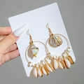 Detail of beach-style hoop earrings featuring natural seashells and conch pendants - Big Round Loop Pendant Shell Style (29357-G)