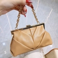 Light brown pleated clutch bag with gold chain strap held by hand for elegant evening events - Brown