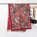 Close-up of red paisley pattern shawl with fine fringe detail on an elegant hanger - Paisley Red Brown