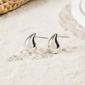 Close-up of polished silver teardrop earrings with shiny metallic finish on textured surface - Minimalist Polished Teardrop Studs (28578-5-silver)