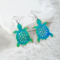 Detail of sea turtle drop earrings with gradient metallic finish on white pebbles - Iridescent Hollow Sea Turtle (29227-5)