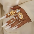 Detailansicht von sieben goldfarbenen Legierungsringen mit weißen Perlen am Modell - Gold Mode Perle Ring-Set (29559-G)