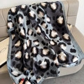 Blue-grey leopard print silk scarf with luxury glossy finish shown on a soft beige sofa - Blue