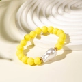 Detail of yellow beaded bracelet featuring a baroque pearl on a white display stand - Yellow