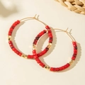 Detail of red beaded hoop earrings with gold accents in a bohemian style - Red