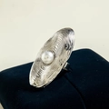 Detailed view of silver oval ripple ring with a central white pearl on navy velvet - Silver - Ripple Texture Pearl Style (29458-5-S)