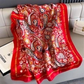 Détail d'une écharpe en soie rouge à motifs paisley sur un banc en cuir - 80*178cm / Rouge