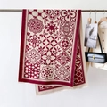 Dettaglio di sciarpa bohémien rossa e crema con intricati motivi floreali e nappe eleganti - Rosso