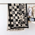 Detail of floral and checkerboard patterned scarf with delicate fringes on a hanger - Black