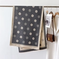 Detailed close-up of camellia print scarf with fringe edges on a metal hanger - Gray