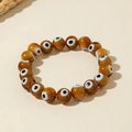 Detailed view of bohemian amber-toned evil eye beads on a flexible elastic bracelet - Faceted Brown (30529-bra-brown-2)