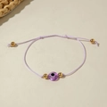 Detail of purple woven evil eye bracelet with gold beads on a minimalist background - Purple Braided Rope (30532-bra-pur-10-EP)