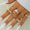 Close-up of seven gold stacked rings with faux pearls and rhinestones on fingers - 7-Piece Gold Artificial Pearl and Rhinestone Set (30510-ring-G)