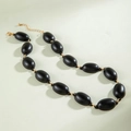Detailed view of matte black oval beads with gold metal links and adjustable clasp - Black Oval Style