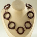 Detail of chunky dark brown wooden ring necklace with golden metal connectors on a bust - Brown Ring Style