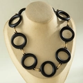 Detailed view of matte black acrylic rings with gold metal links on a display bust - Black Round Style
