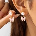 Gros plan de boucles d'oreilles papillon en émail rose avec perles blanches sur modèle - Boucles d'Oreilles Clous Perle Blanche Papillon Rose (30573-ear-white-EP)