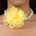 Detail of a large yellow fabric flower and double-row white faux pearl necklace on model - Yellow