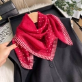 Luxurious red polka dot silk scarf with striped edges shown on a black suit vest - Red
