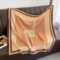 Dettaglio della trama di una sciarpa a quadri su un divano in pelle marrone - 90*90cm / Arancione