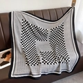 Dettaglio del foulard in seta a scacchi con texture morbida e motivi vintage su divano - 90*90cm / Nero