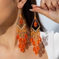 Dettaglio di orecchini boho arancioni con perline di vetro e montatura in metallo traforata - Arancione Brillante (30335-ear-orange-EP)