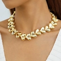 Close-up of a chunky polished golden heart link necklace worn by a fashion model - Single Necklace / Gold