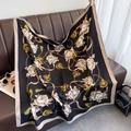 Detailed shot of camellia silk scarf draped on a sofa showing glossy fabric texture - Black