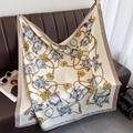 Détail d'un foulard en soie à motif camélia et chaîne dorée sur fond de cuir - Blanc