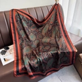 Large paisley print silk shawl in burnt orange and black on a leather sofa surface - 90*90cm / Red Border (DM-48)