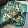 Detailaufnahme eines smaragdgrünen Seidenschals mit Paisley-Muster auf Leder - Grün