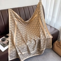 Elegant geometric stripe silk scarf draped on a leather sofa with stylish accessories - Khaki