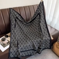 Detail of black and white geometric silk scarf draped on a luxury leather sofa - Black