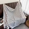 Elegant black and white four-leaf clover patterned silk scarf draped over a sofa - White