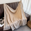 Detail of elegant champagne silk scarf with geometric flower patterns on a leather sofa - Khaki