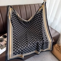 Detail of a luxury twill silk scarf with geometric clover patterns on a leather sofa - Black