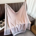 Close-up of light pink silk scarf with floral patterns and striped edges on a leather sofa - Pink