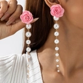 Detail van elegante roze stoffen roos oorbellen met lange faux parel kwastjes - Lichtroze